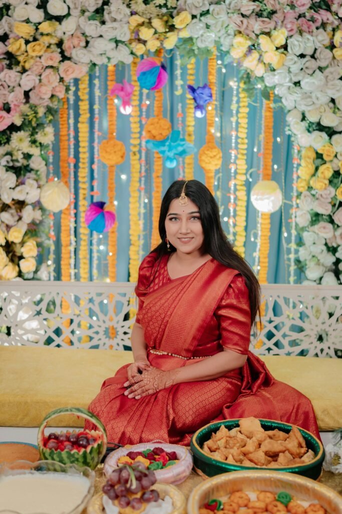 Woman in a saree enjoying a festive occasion with vibrant floral decorations.